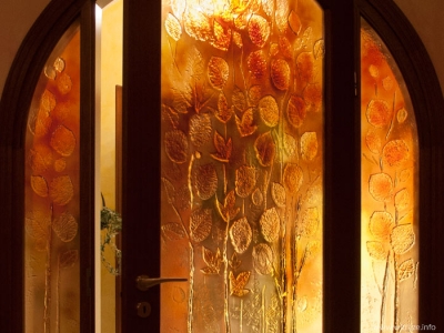 Szkło artystyczne w kolorach jesieni wypełnia drzwi i ścanę szklaną